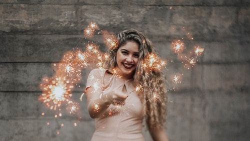 Free Smiling woman with blonde hair holding sparklers in an outdoor setting at night. Stock Photo