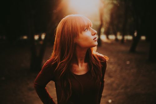 Free A thoughtful woman looks upward in a serene park setting during sunset. Stock Photo
