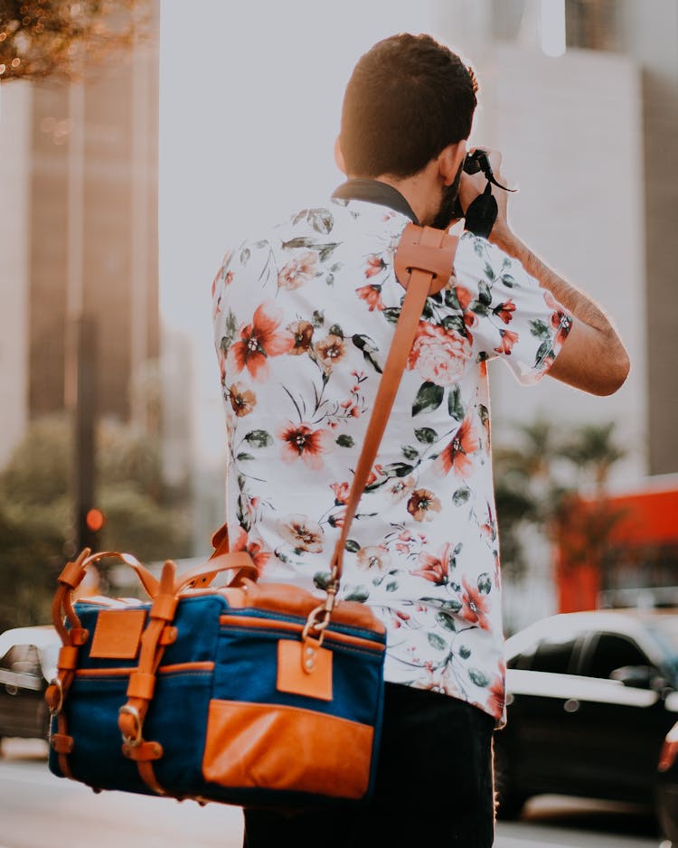 Man With Bag Taking Pictures With Camera On Street