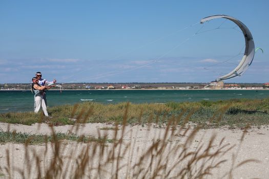 Man and woman learning kite surfing on a breezy beach day.