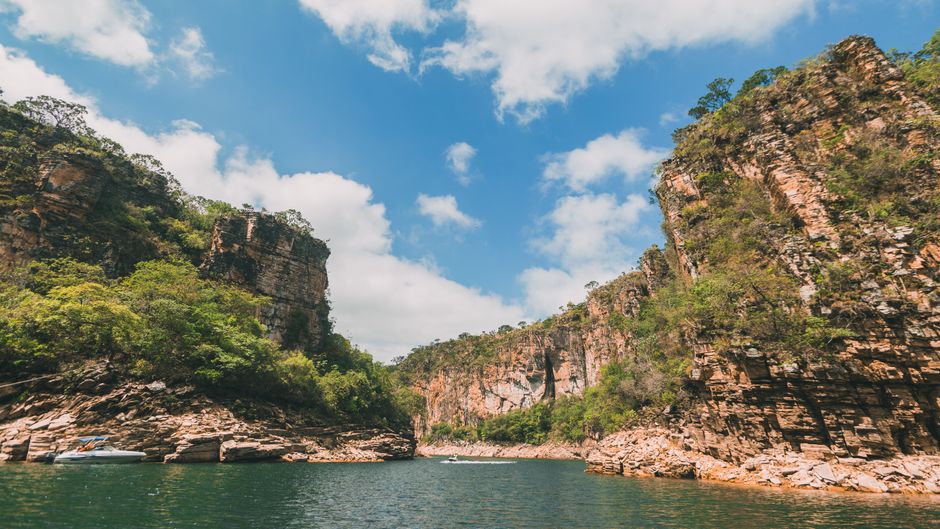 A small wooden boat floating on incredibly clear turquoise water between sheer cliff walls