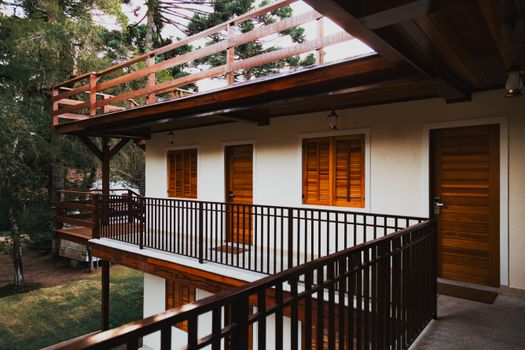 Serene wooden lodge featuring balconies, doors, and windows surrounded by lush greenery.