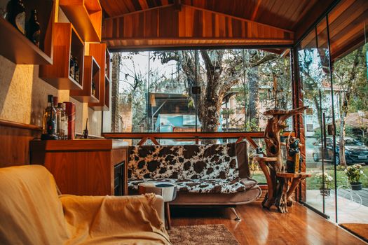 A modern living room with natural wood decor and floor-to-ceiling windows.