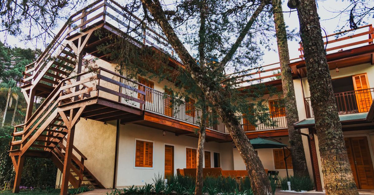 A picturesque wooden terrace house nestled amongst lush trees under a clear sky, capturing the tranquility of nature.