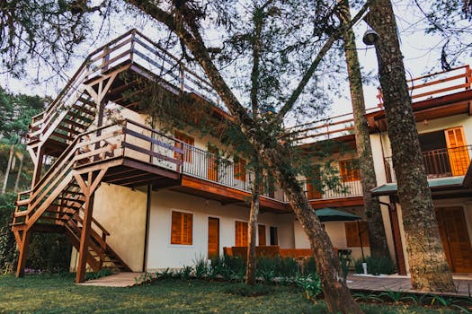 A picturesque wooden terrace house nestled amongst lush trees under a clear sky, capturing the tranquility of nature.