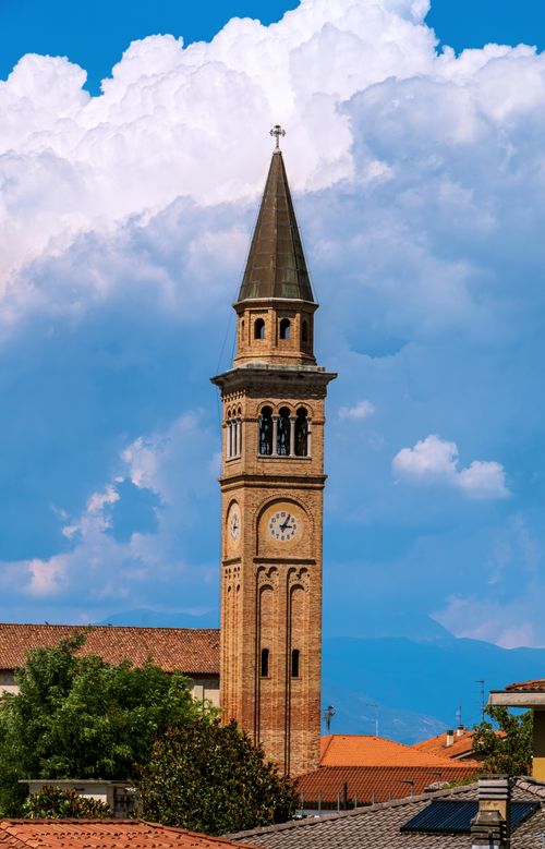 Free Vertical shot of the clock tower in Cimadolmo, Veneto, Italy against a bright blue sky. Stock Photo