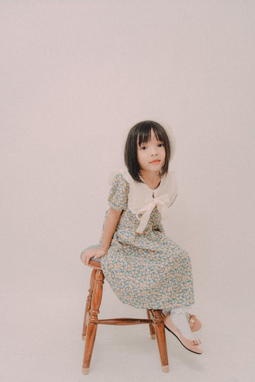 Girl in Floral Dress Sitting on a Chair 