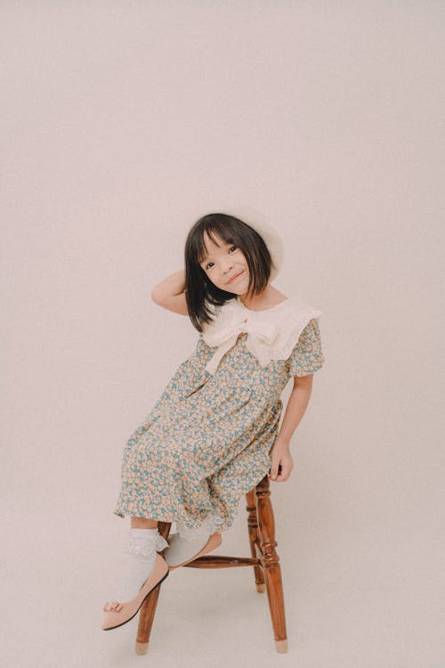 Girl in Floral Dress Sitting on Wooden Chair