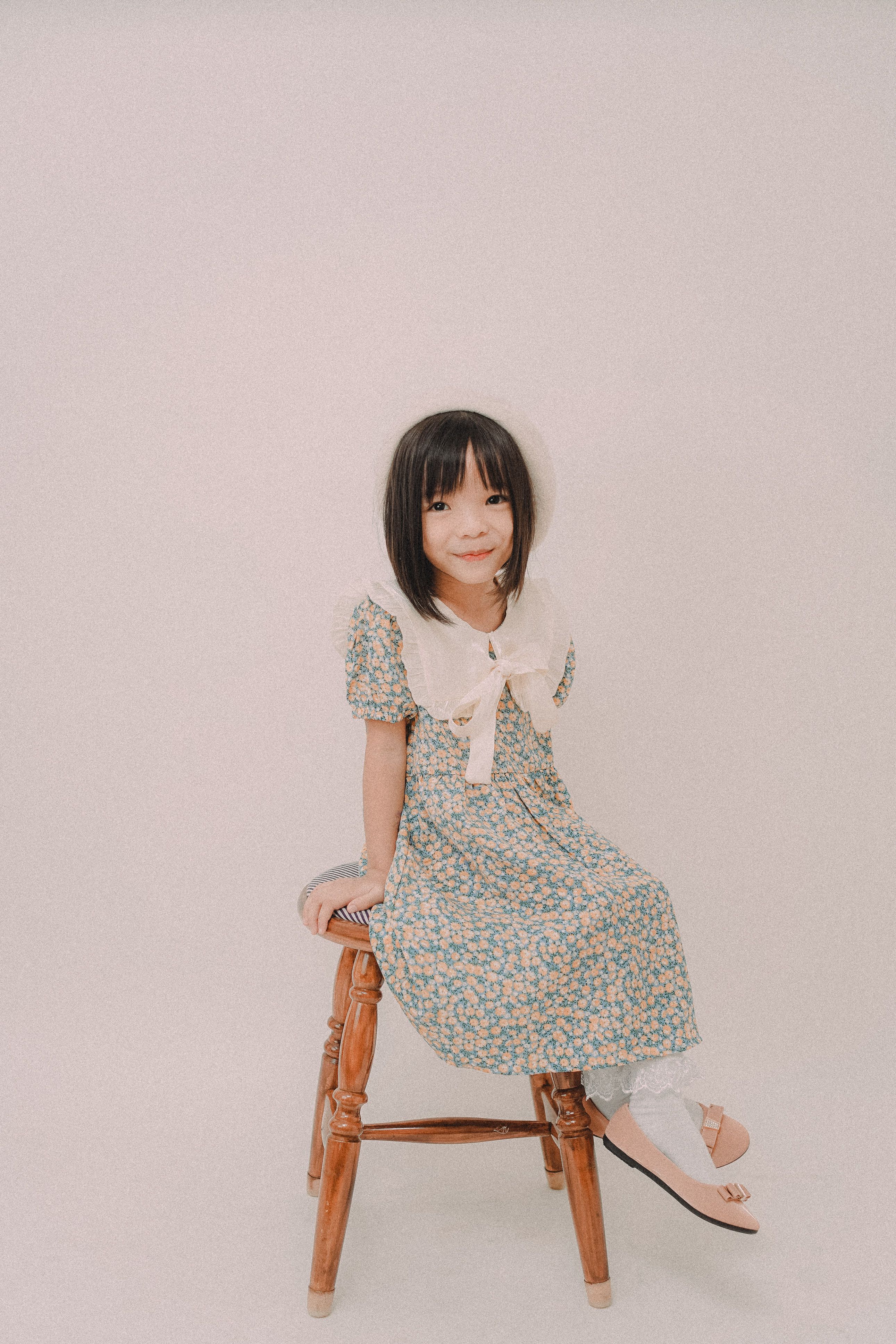Girl in Floral Dress Sitting on Wooden Chair · Free Stock Photo