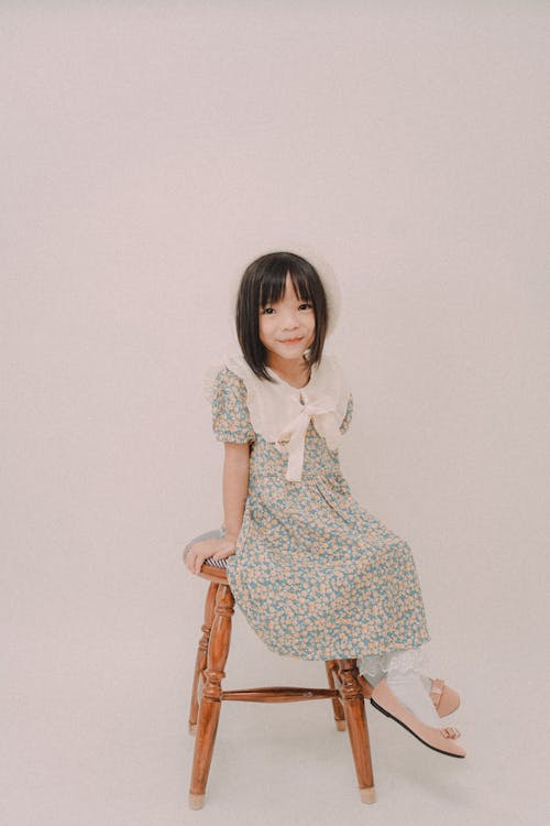 Girl in Floral Dress Sitting on Wooden Chair