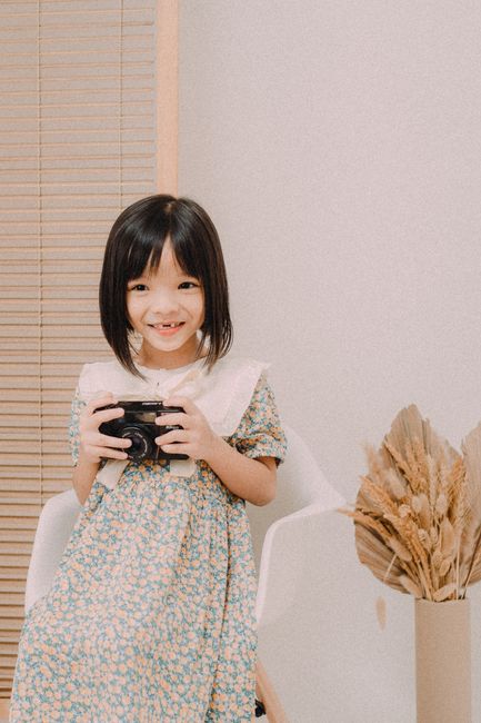 Cute child with camera in a bright room, showcasing joy and creativity.