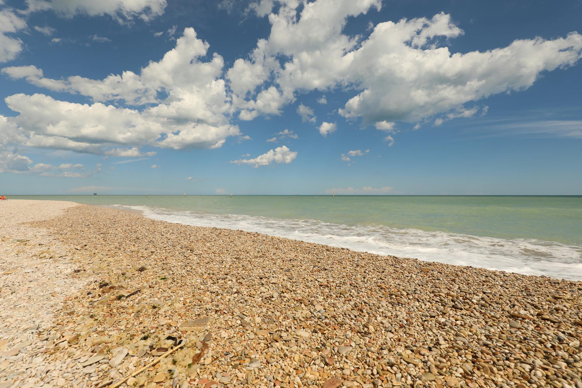 Scenic view of Porto Sant'Elpidio pebble beach with clear blue sky and white clouds.