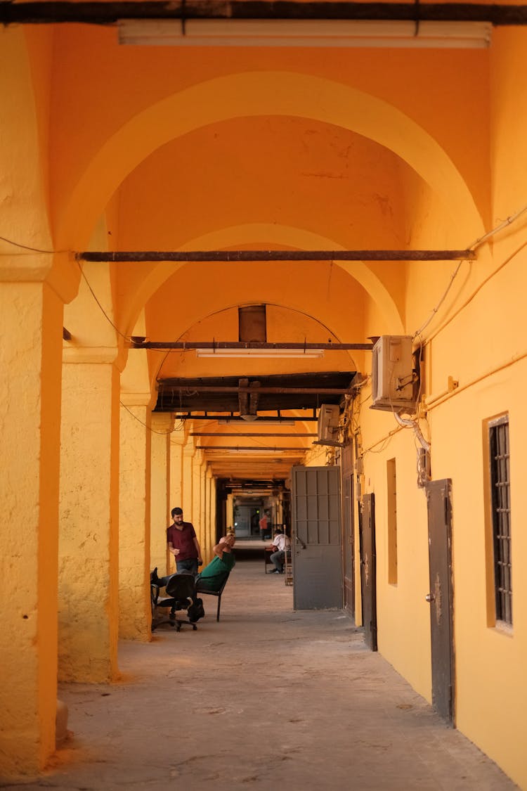 People Standing And Sitting On Outside Hallway Of A Building