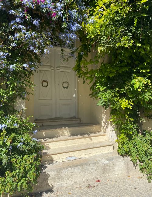 Free Beautiful doorway surrounded by lush greenery and flowers in Bozcaada, Turkey. Stock Photo