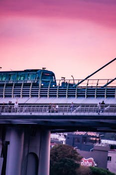 Metro train crosses Halic Bridge in Istanbul during a vibrant pink sunset, capturing urban travel.