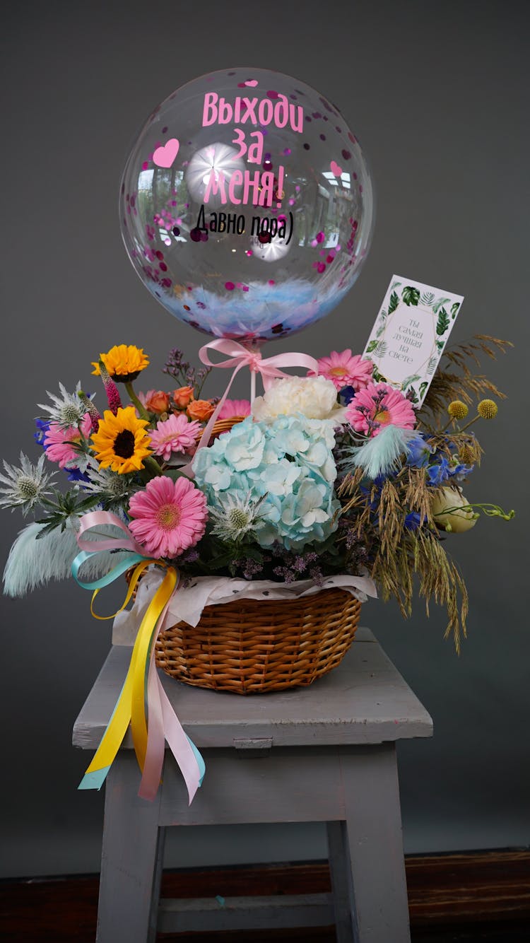 A Basket Of Assorted Flowers And A Balloon