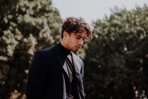 Free Stylish man in a suit and turtleneck in a serene outdoor setting. Stock Photo