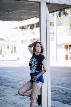 Stylish woman in urban setting wearing fishnet and shorts, exuding modern fashion vibe.