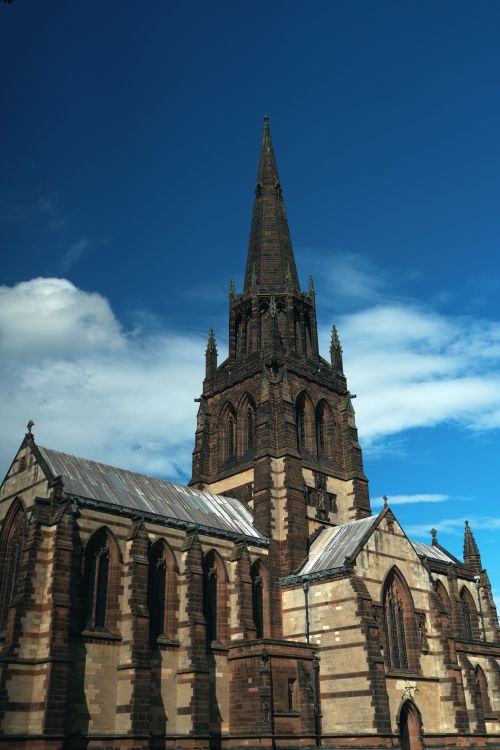 Free Majestic Gothic church with stunning spire under a blue sky, ideal for architectural themes. Stock Photo