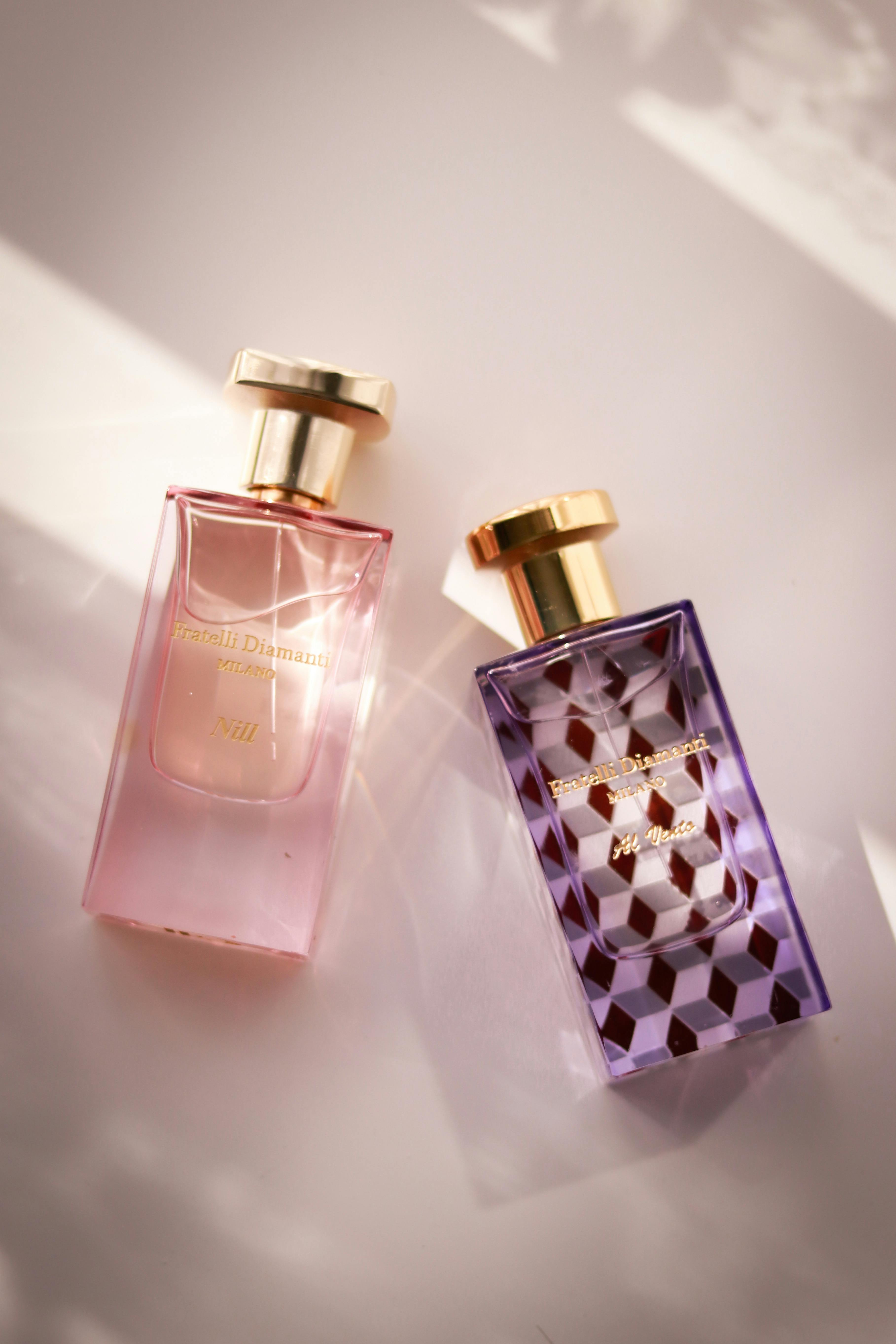 Close-up of two elegant glass perfume bottles with soft lighting, highlighting their design.