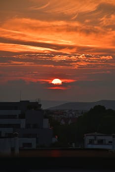 Dramatic sunset view of the Cluj-Napoca skyline with vibrant clouds highlighting the evening sky.