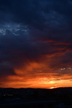 Vibrant sunset with dramatic dark clouds over Cluj-Napoca, creating a vivid skyscape.