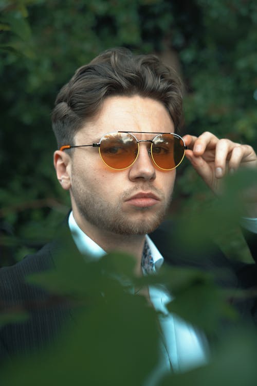 A Man in Suit Wearing Aviator Sunglasses while Looking at the Camera