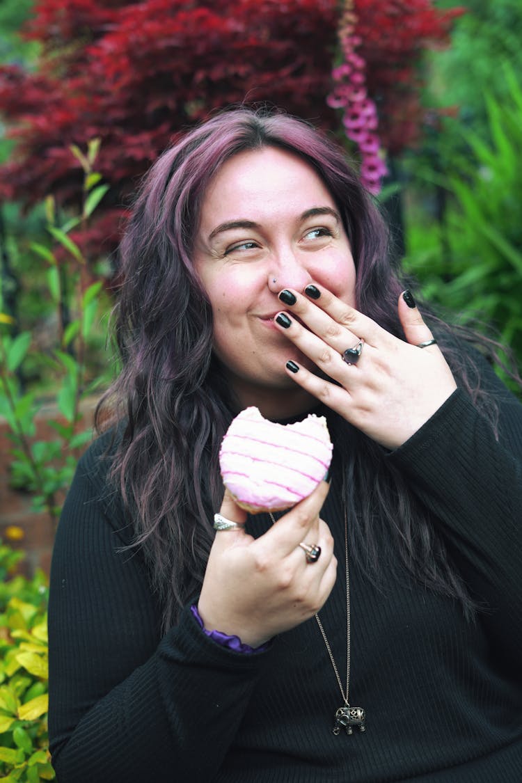 A Woman In Black Sweater Eating A Donut