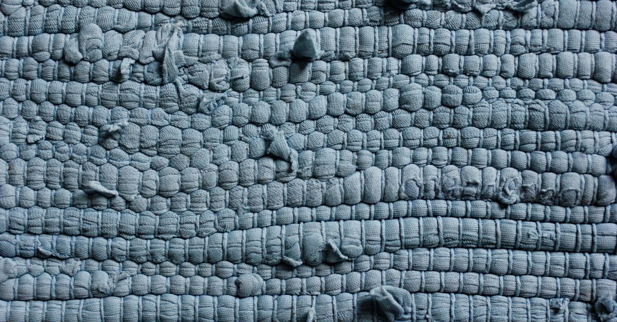 Visão detalhada de um tecido azul texturizado mostrando seu intrincado padrão de entrelaçamento e superfície áspera.