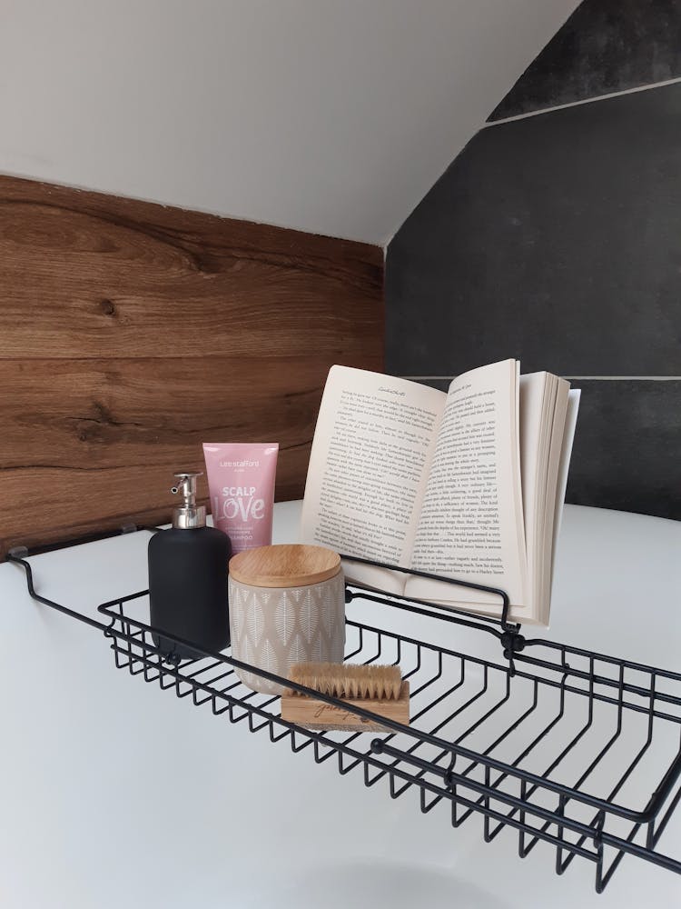 Book And Cleaning Products On Metal Rack Above Bathtub