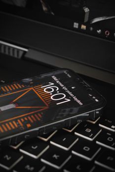 Smartphone placed on a laptop keyboard displaying the time at 16:01.