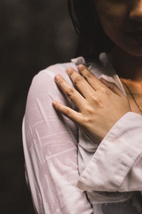 Free A close-up image of a woman's hand resting gently on her shoulder, conveying warmth. Stock Photo