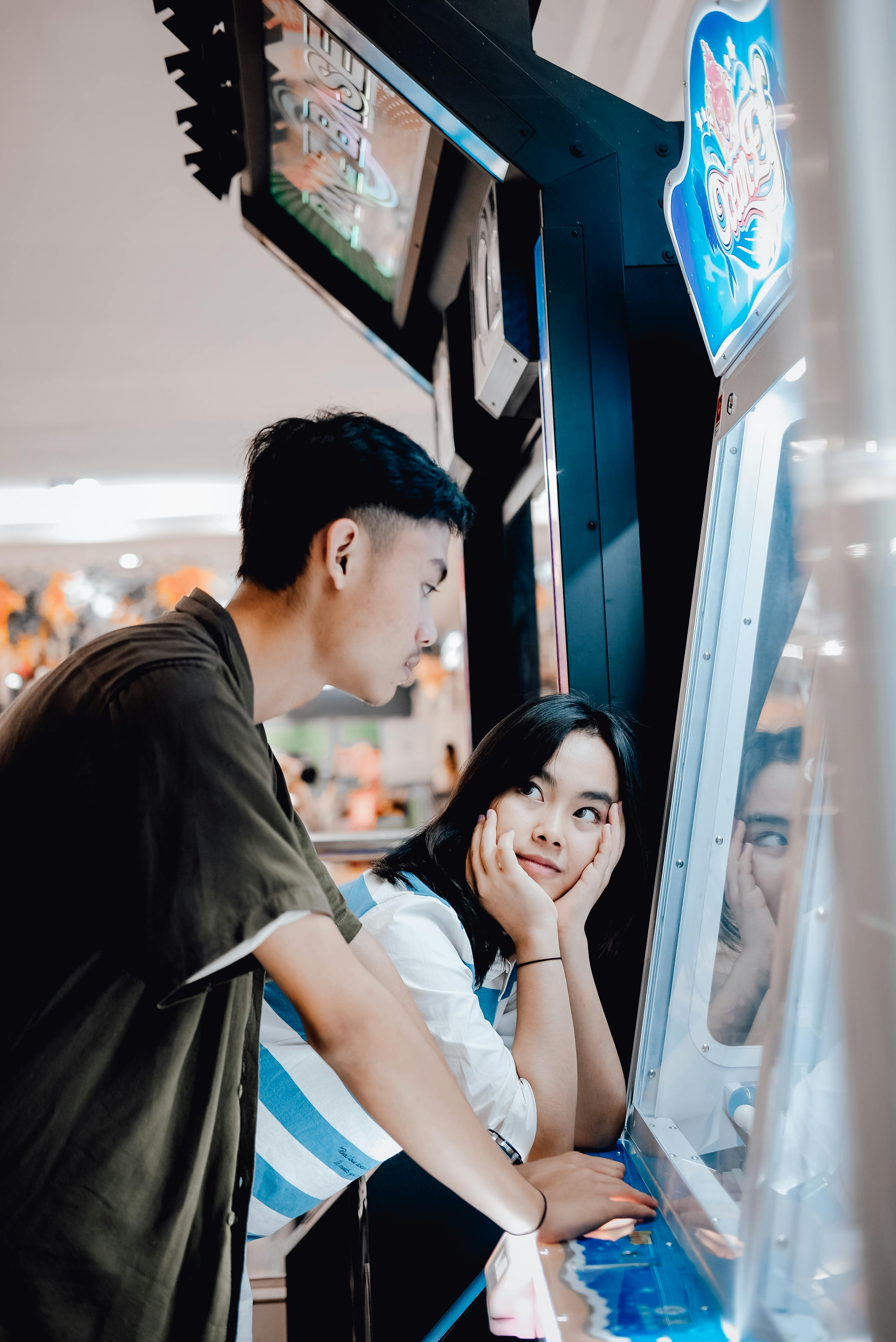 A young couple bonding over an arcade game, enjoying leisure time indoors.