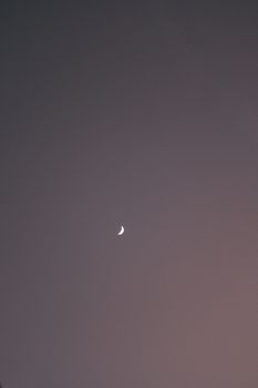 A serene crescent moon against a dark evening sky above Tulum, Mexico, creating a minimalist aesthetic.