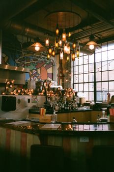 Warm Nashville bar interior featuring chandeliers, a colorful mural, and a stocked counter.