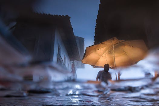 A person with an umbrella walking through rain-soaked streets at night in Cuetzalan, Mexico.