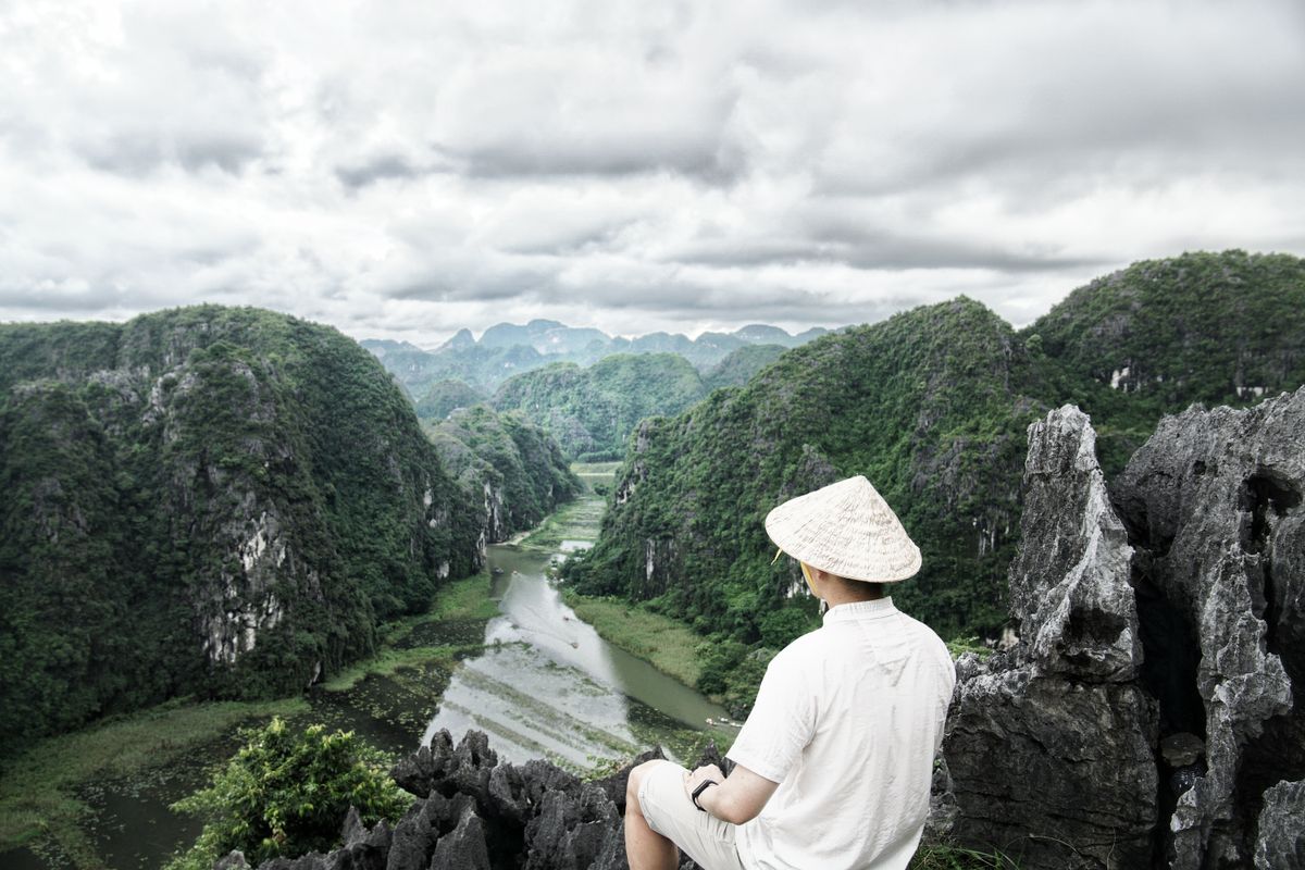 A visitor overlooking limestone hills and a winding river from a high viewpoint in Ninh Binh