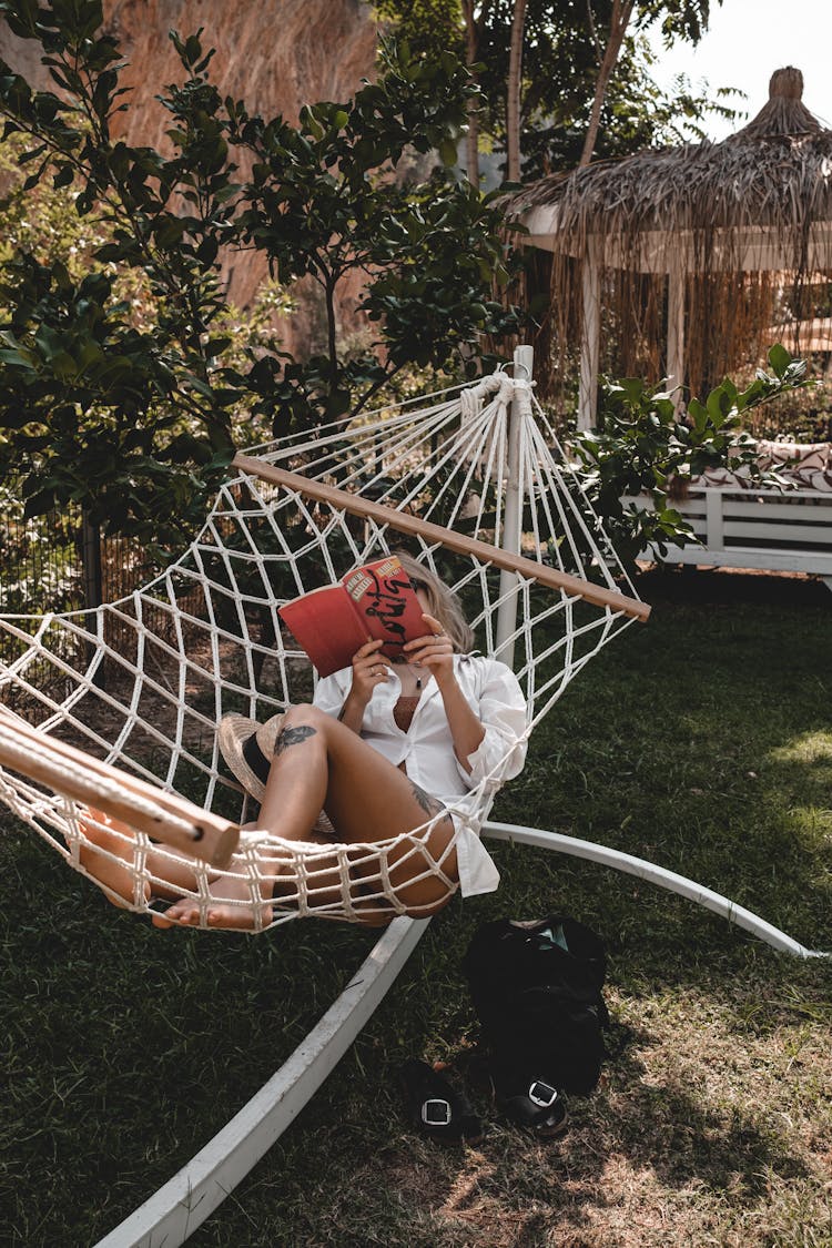 A Person Reading A Book While Sitting In A Hammock