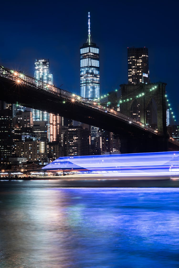 Illuminated Skyscrapers In New York City At Night And View Of The Brooklyn Bridge, New York, USA