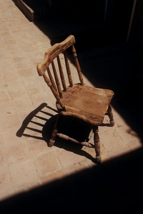 Free A vintage wooden chair casting shadows in a sunny courtyard in Dubai, UAE. Stock Photo