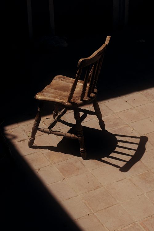 Free A lone wooden chair casting a shadow in a sunlit room in Dubai, UAE. Stock Photo