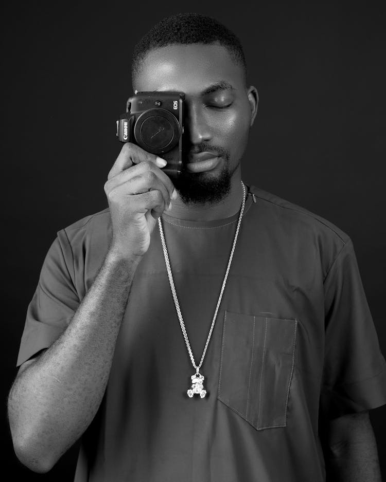 Grayscale Photo Of A Man Covering Eye With A Camera