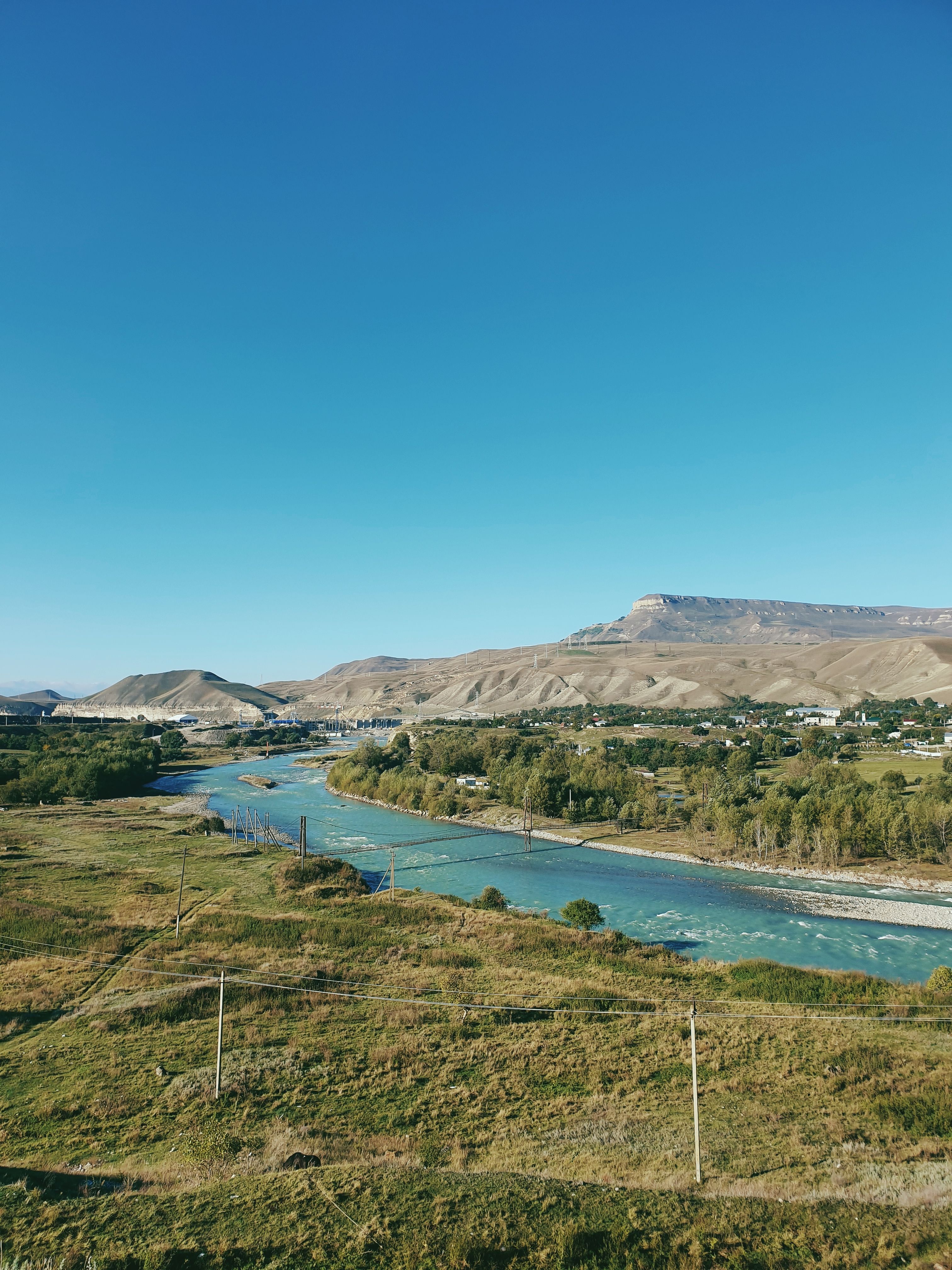 A scenic view of a river flowing through a grassy field with mountains in the background.