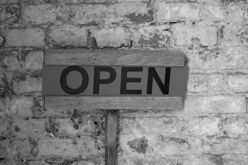 Close-up of a Sign Saying Open on a Brick Wall 