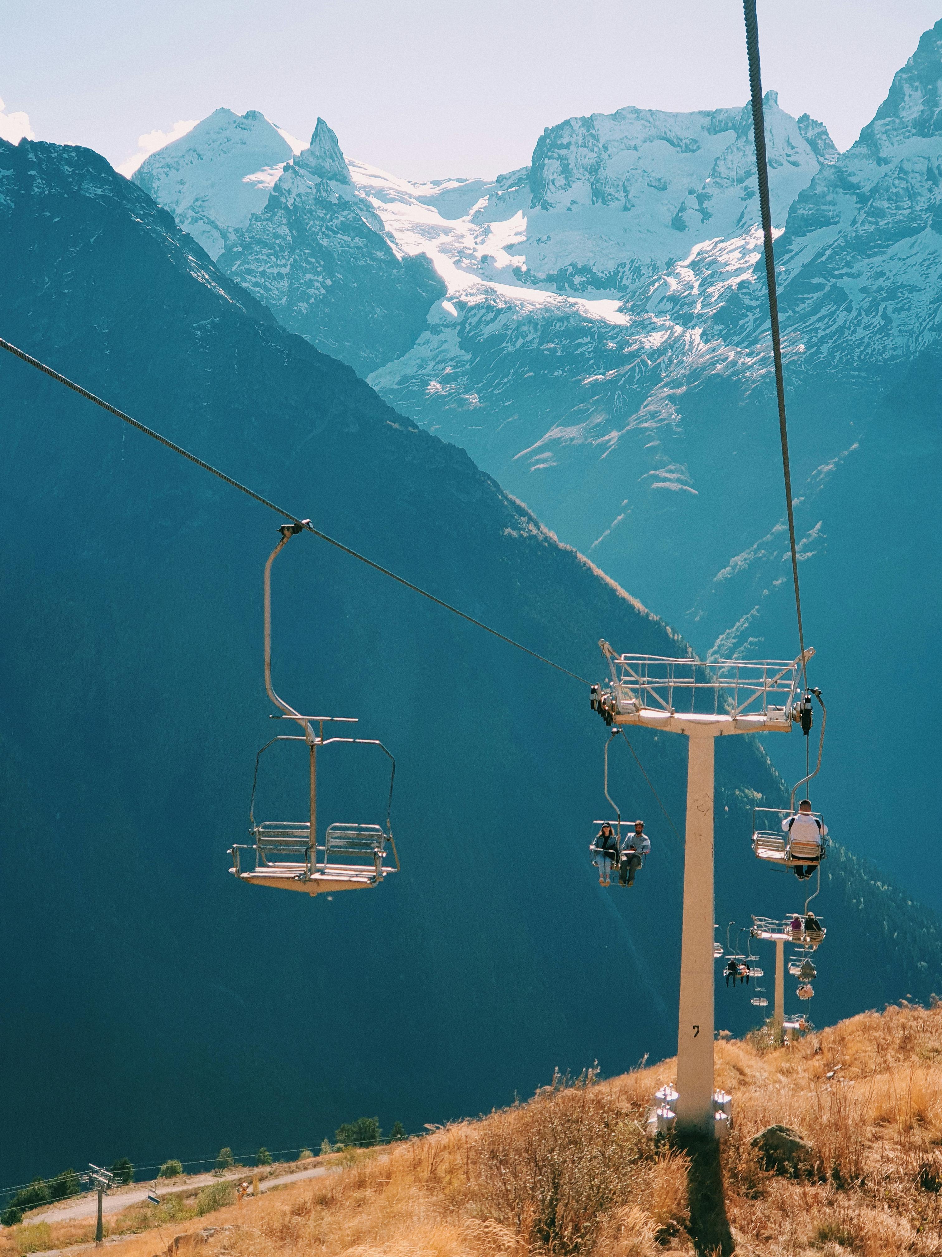 Prescription Goggle Inserts - Cable cars traverse a mountainous landscape with snow-capped peaks in the background, showcasing serene natural beauty.