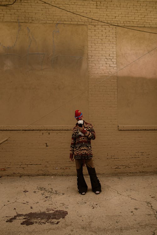 Man Wearing a Face Mask Standing under a White Brick Wall in a Postindustrial Building