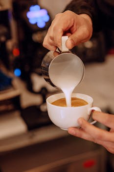 Barista pouring milk into coffee to create latte art at a café in Baku, Azerbaijan.