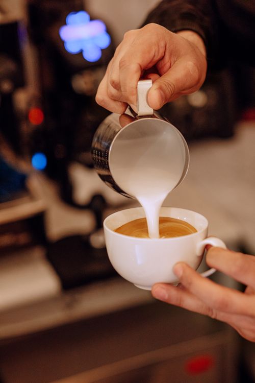 Free Barista pouring milk into coffee to create latte art at a café in Baku, Azerbaijan. Stock Photo