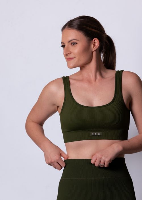 Free Portrait of a woman in olive green activewear on a white background, exuding confidence. Stock Photo