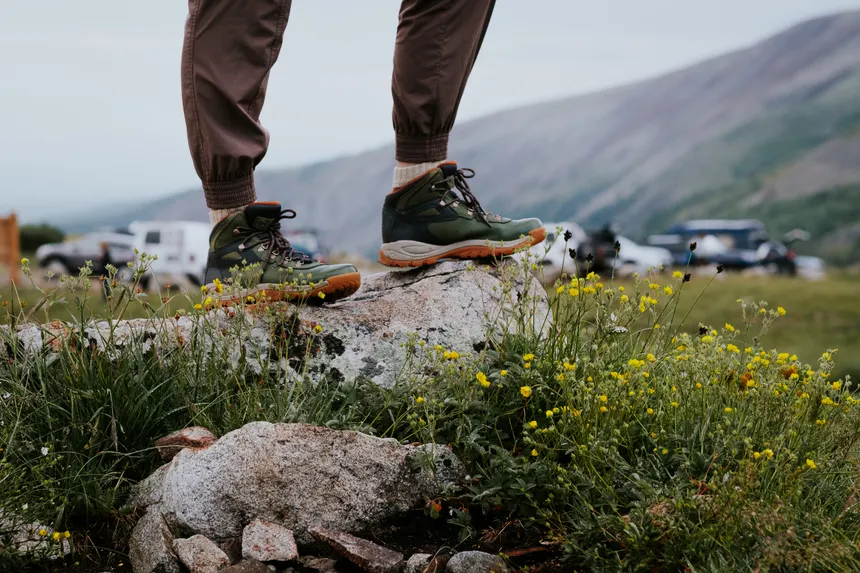 Close-up of hiking boots on a rocky outcrop surrounded by wildflowers in Alma, Colorado.